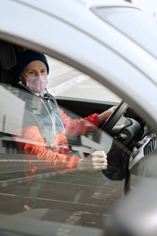man driving car while wearing a mask